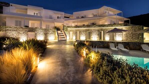 Una villa moderna con piscina, mobiliario exterior y una escalera que lleva a los niveles superiores.