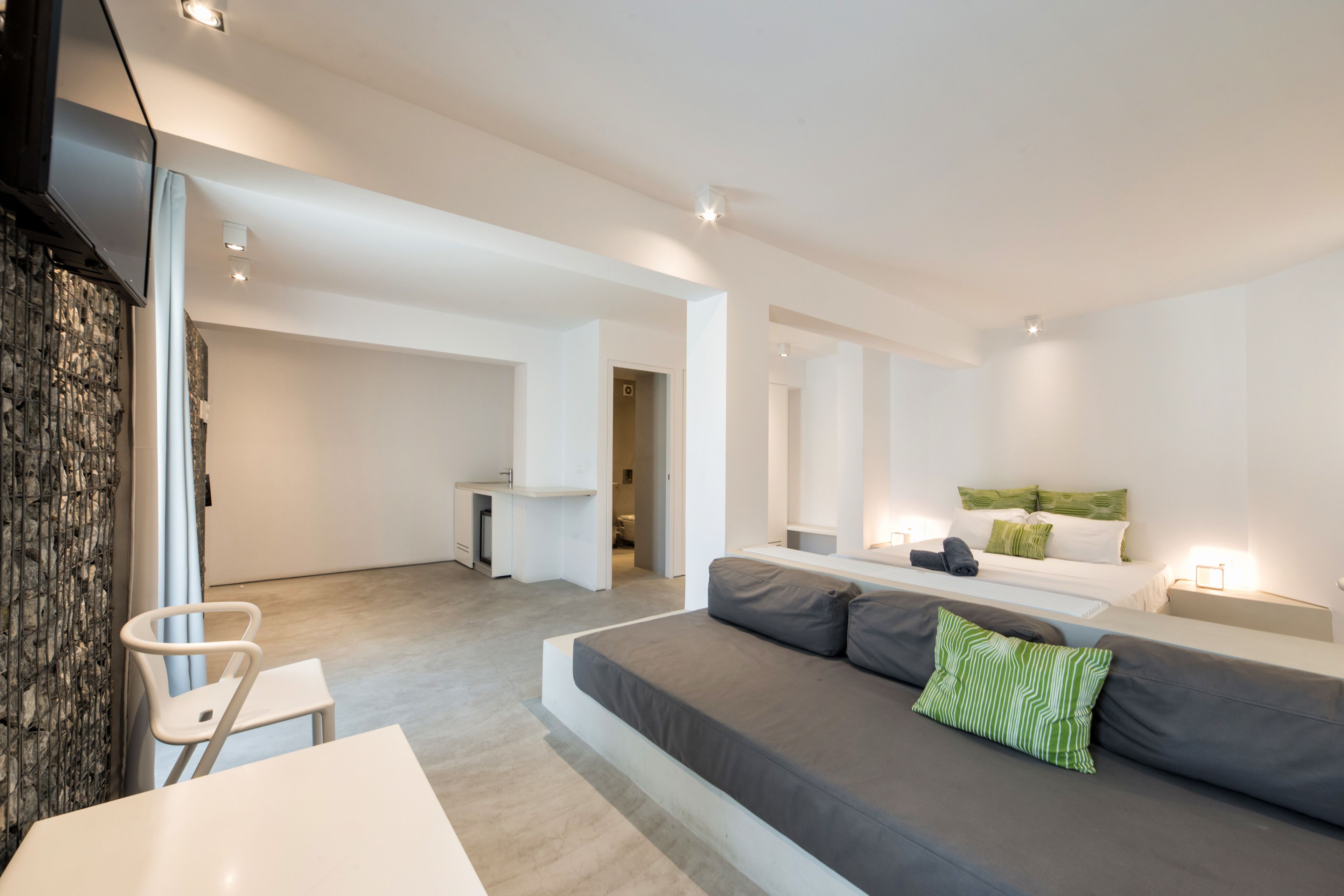 A modern, minimalist living room with a sofa, a small table, and a TV mounted on the wall.