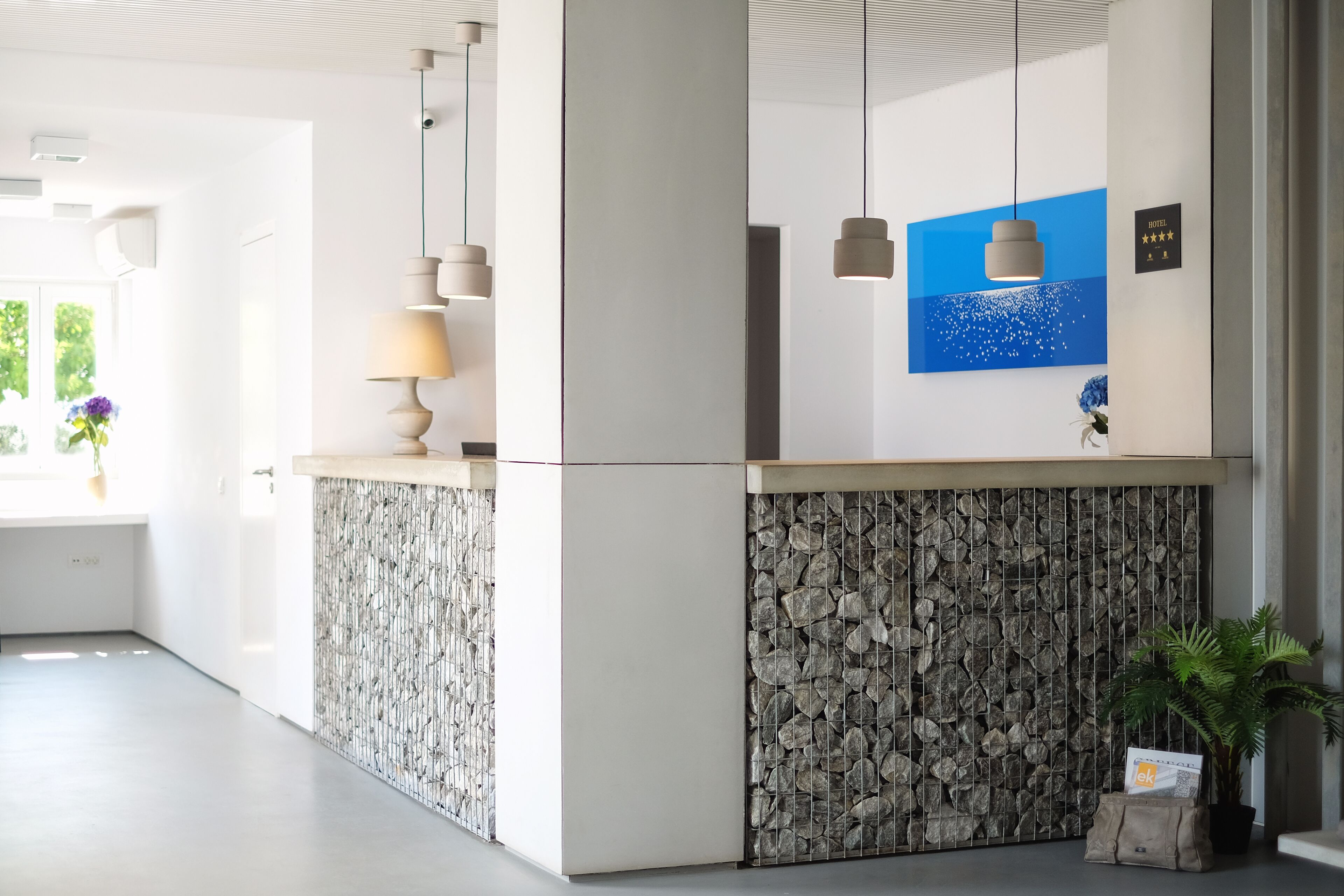 A modern reception area with a stone-textured wall, a blue painting, and a plant.