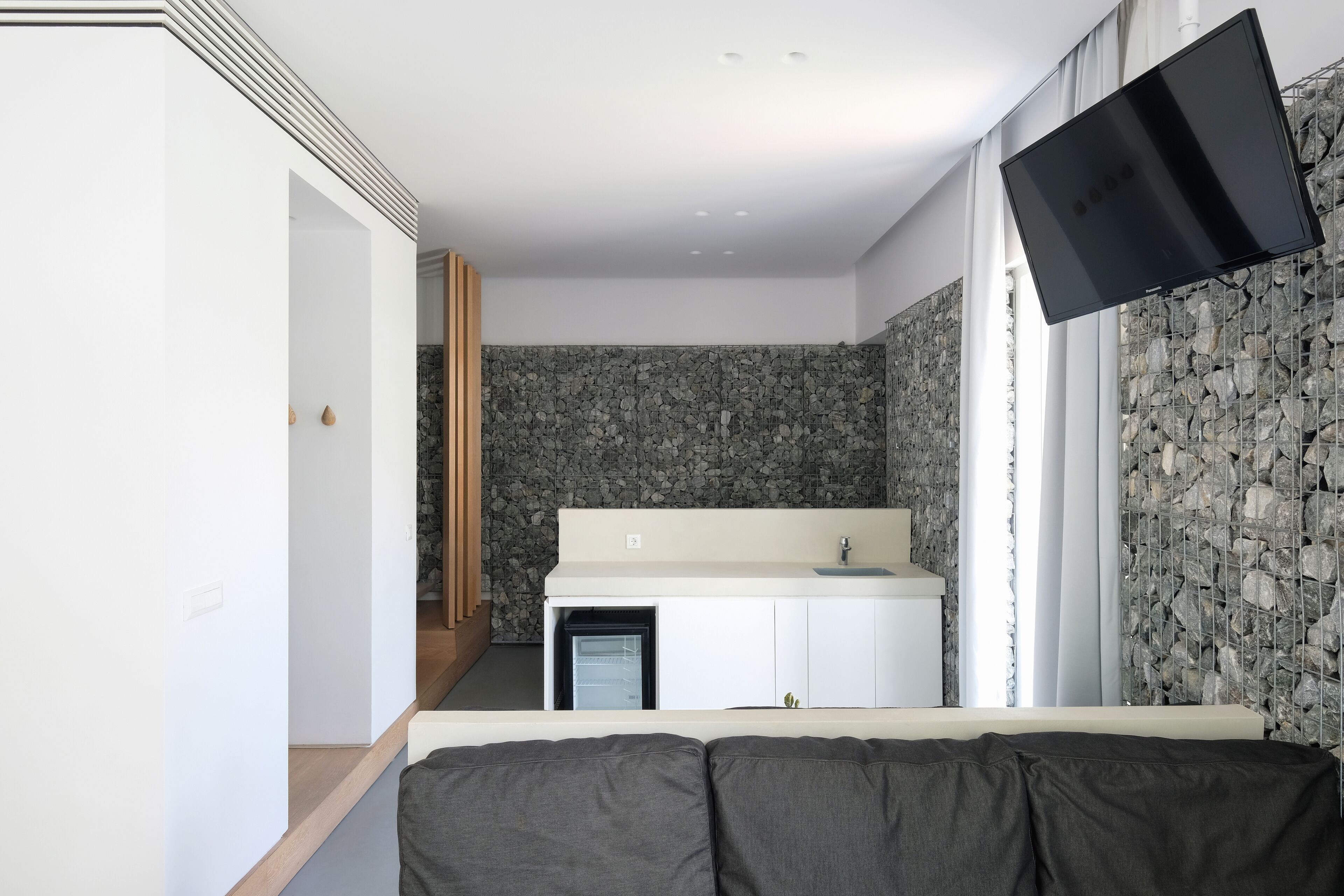 Ein modernes Badezimmer mit Steinwand, Waschbecken und Spiegel.