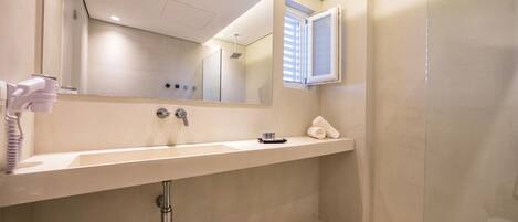 Een moderne badkamer met een grote spiegel, een wastafel en een douche.