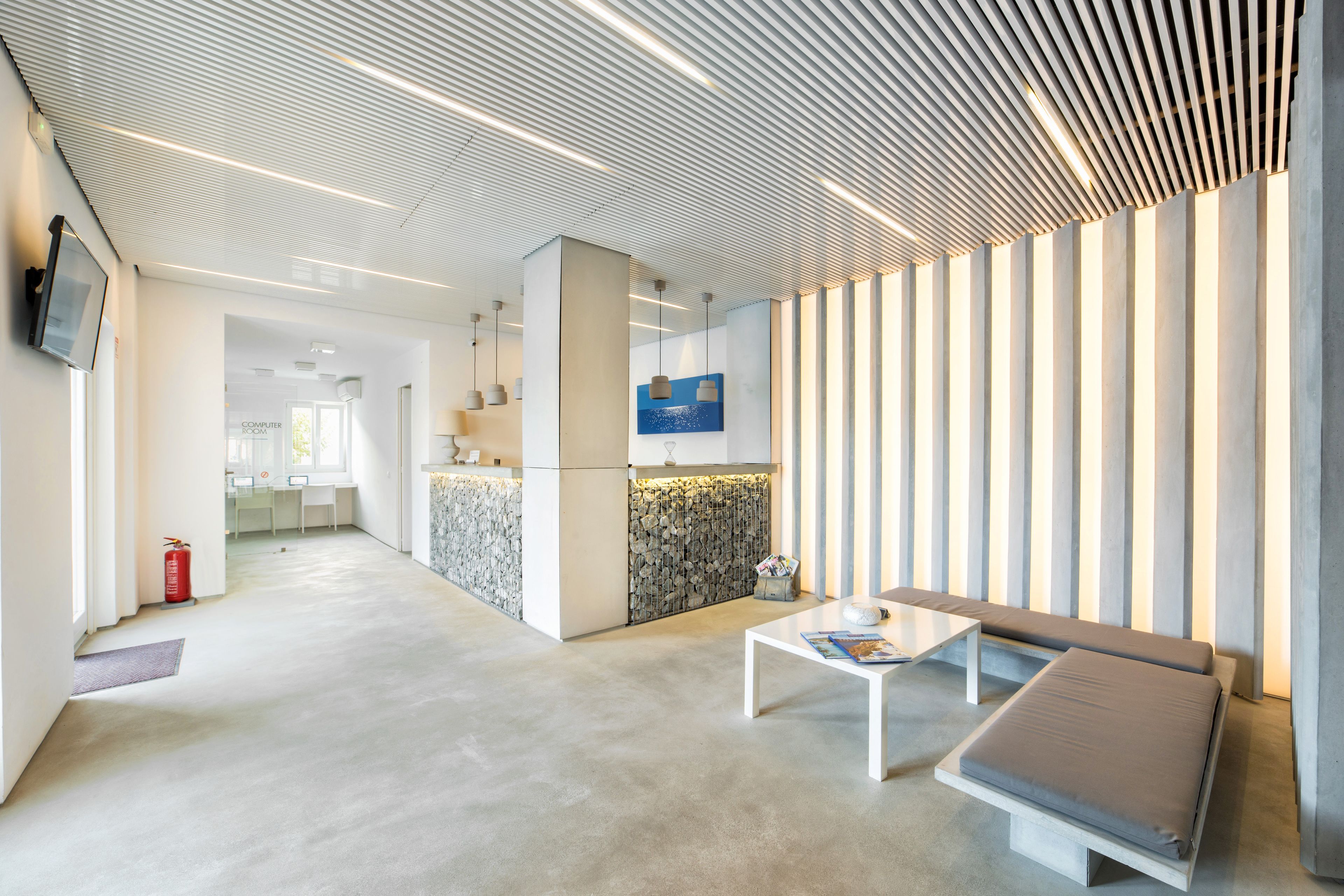 A modern lobby with a reception desk, seating area, and a patterned wall.