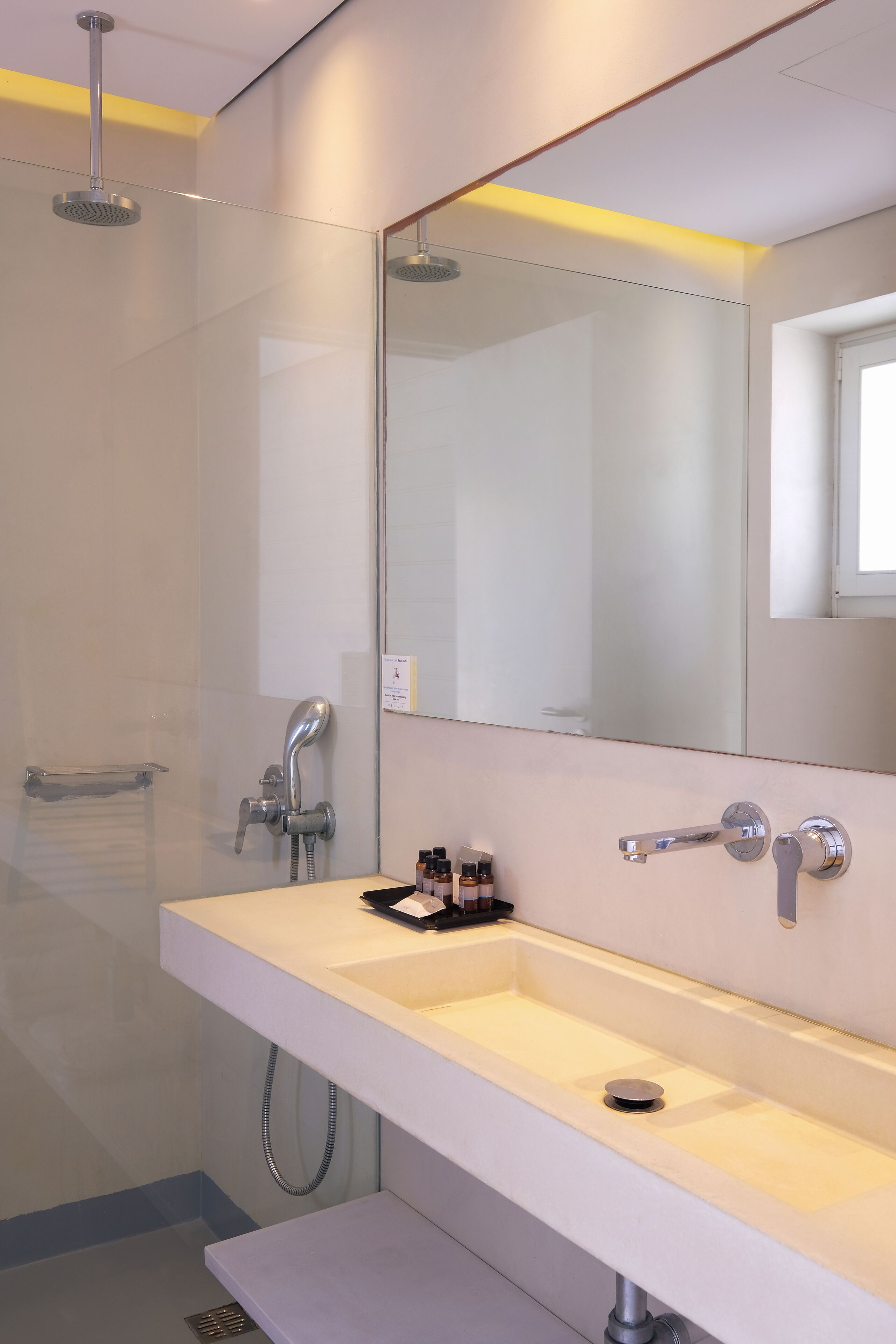 A modern bathroom with a large mirror, a white sink, and a shower.