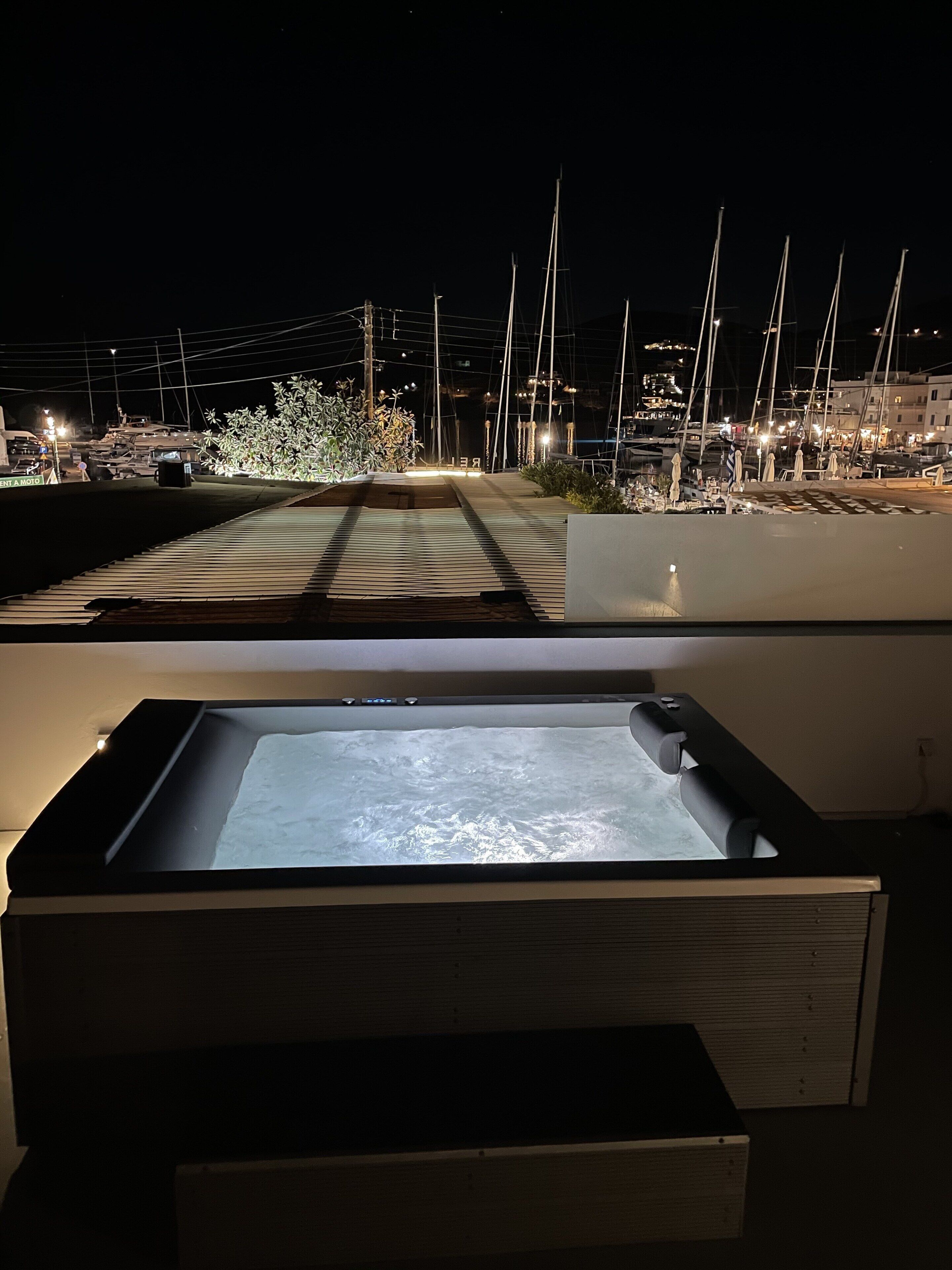 Un bain à remous avec vue sur une marina, de nuit.