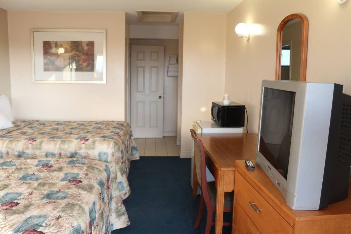 Une chambre d’hôtel équipée d’un lit, d’un bureau, d’une télévision et d’un miroir.