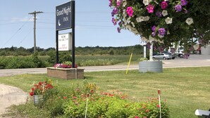 A parking lot with a sign for 'Good Night Inn' and a large flower display. - Good Night Inn (Port Colborne)