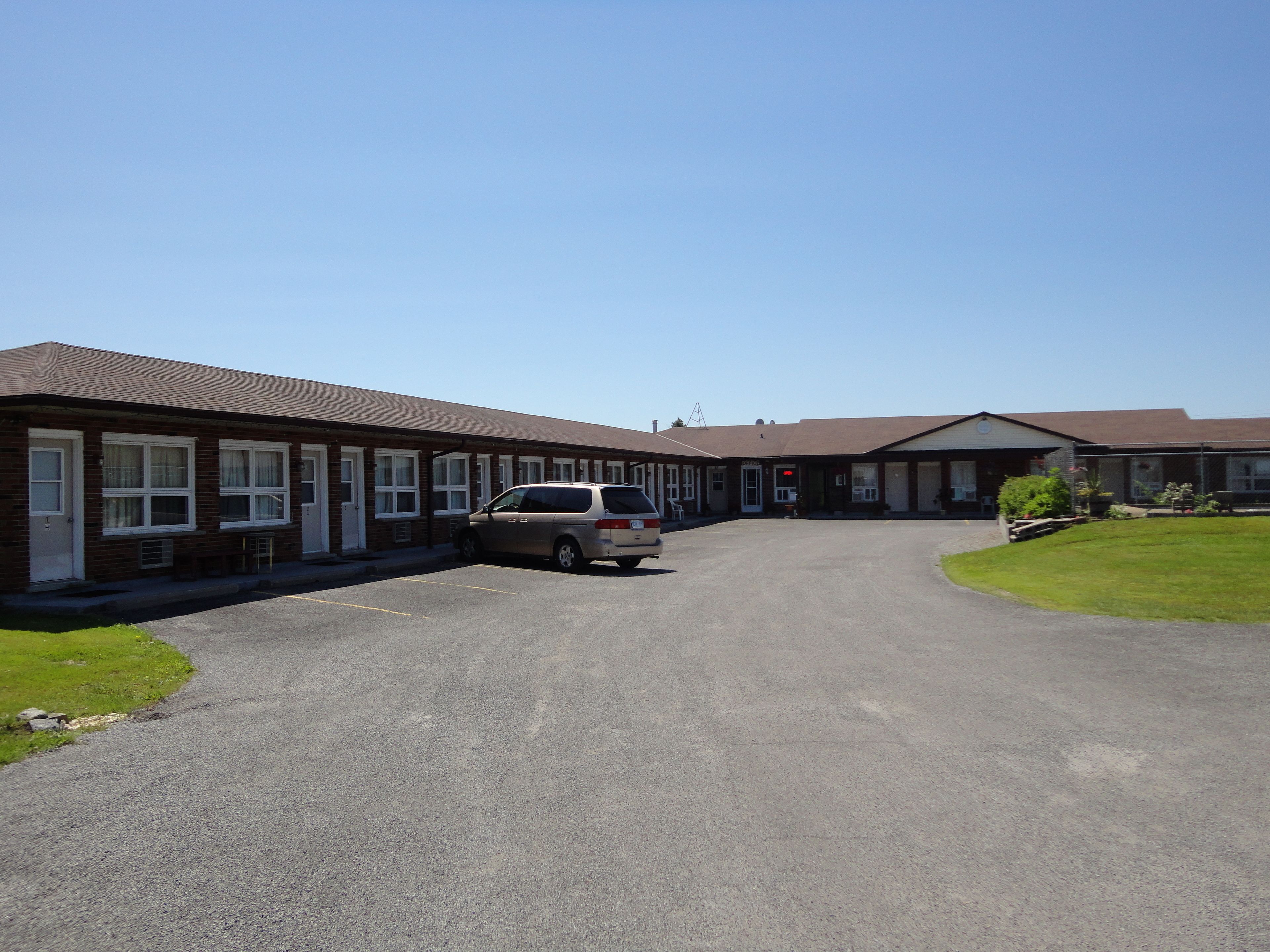 A motel with multiple rooms, a parking area, and a small lawn.
