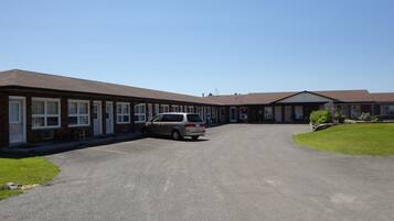 A motel with multiple rooms, a parking area, and a small lawn.