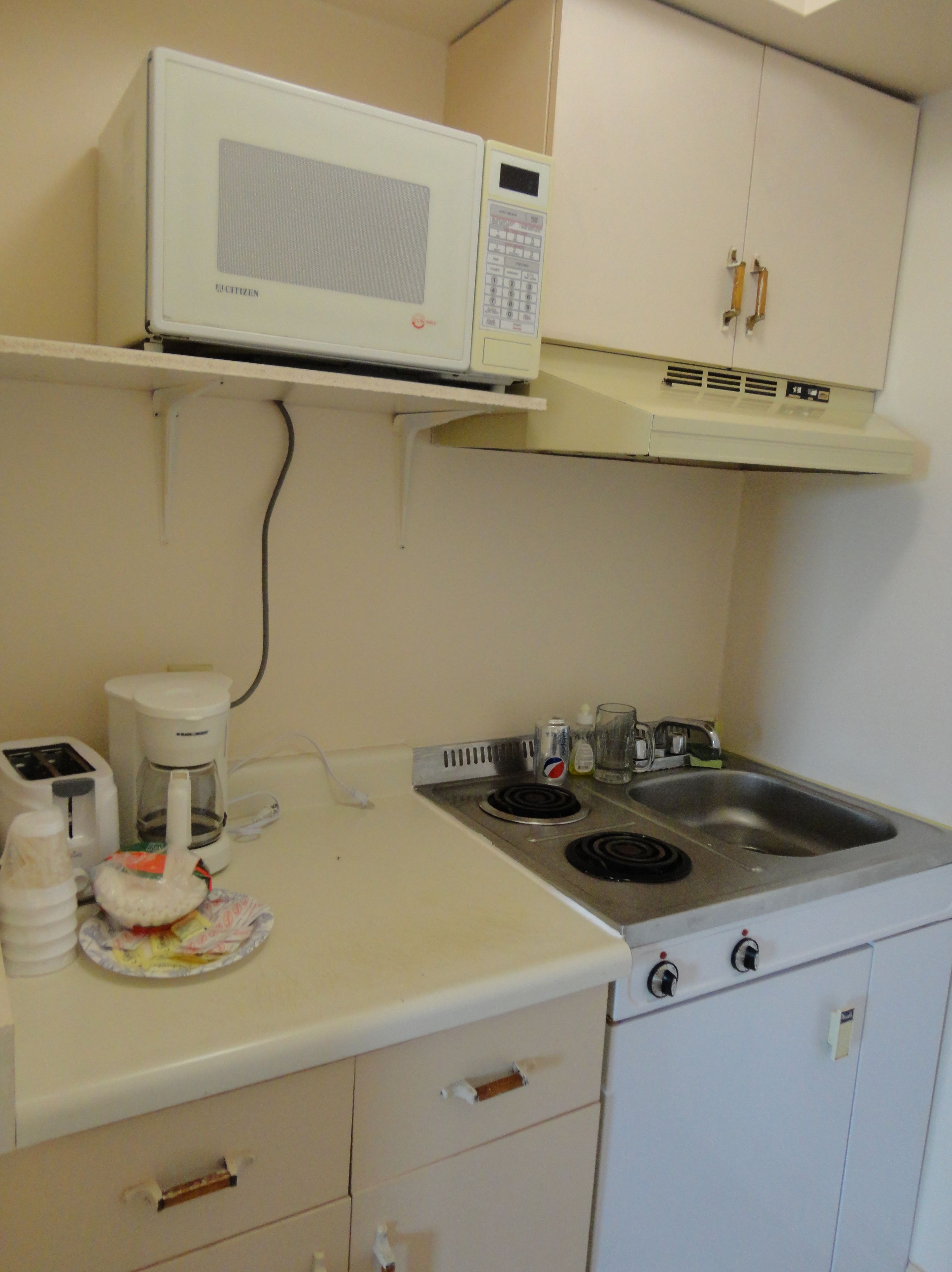 A kitchenette with a microwave, toaster, coffee maker, and a sink.
