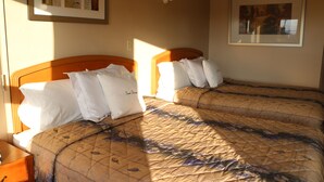 A hotel room with two beds, each with a wooden headboard, and a framed picture on the wall. - Good Night Inn (Port Colborne)