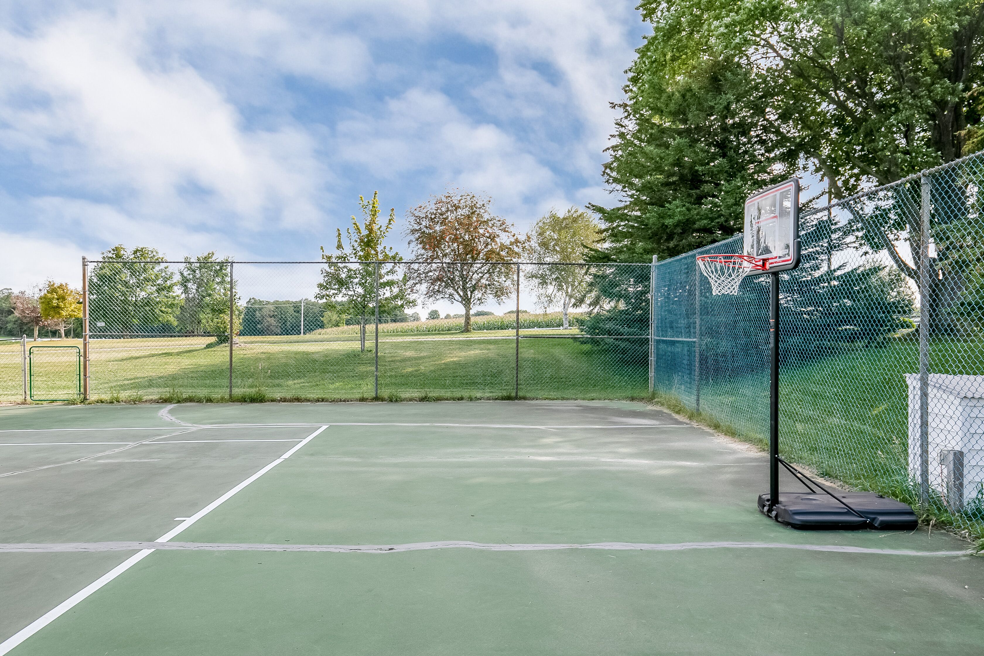 Un terrain de basket-ball en plein air, équipé d’un filet, d’un panier et d’une clôture.