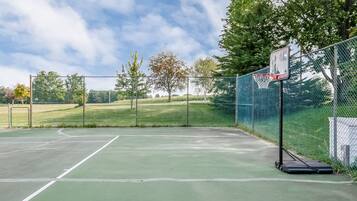 Un terrain de basket-ball en plein air, équipé d’un filet, d’un panier et d’une clôture.