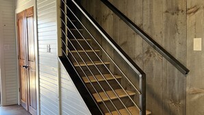 A staircase with metal railings and wooden steps, leading to a room with white walls and a wooden door. - Hideout on the Horseshoe (New Braunfels)