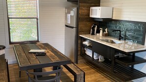 A compact kitchen with a wooden table, a refrigerator, a microwave, and a coffee maker. - Hideout on the Horseshoe (New Braunfels)