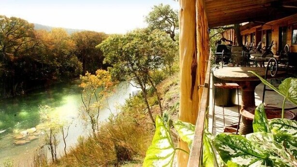 A wooden cabin with a view of a river and surrounding trees. - Hideout on the Horseshoe (New Braunfels)