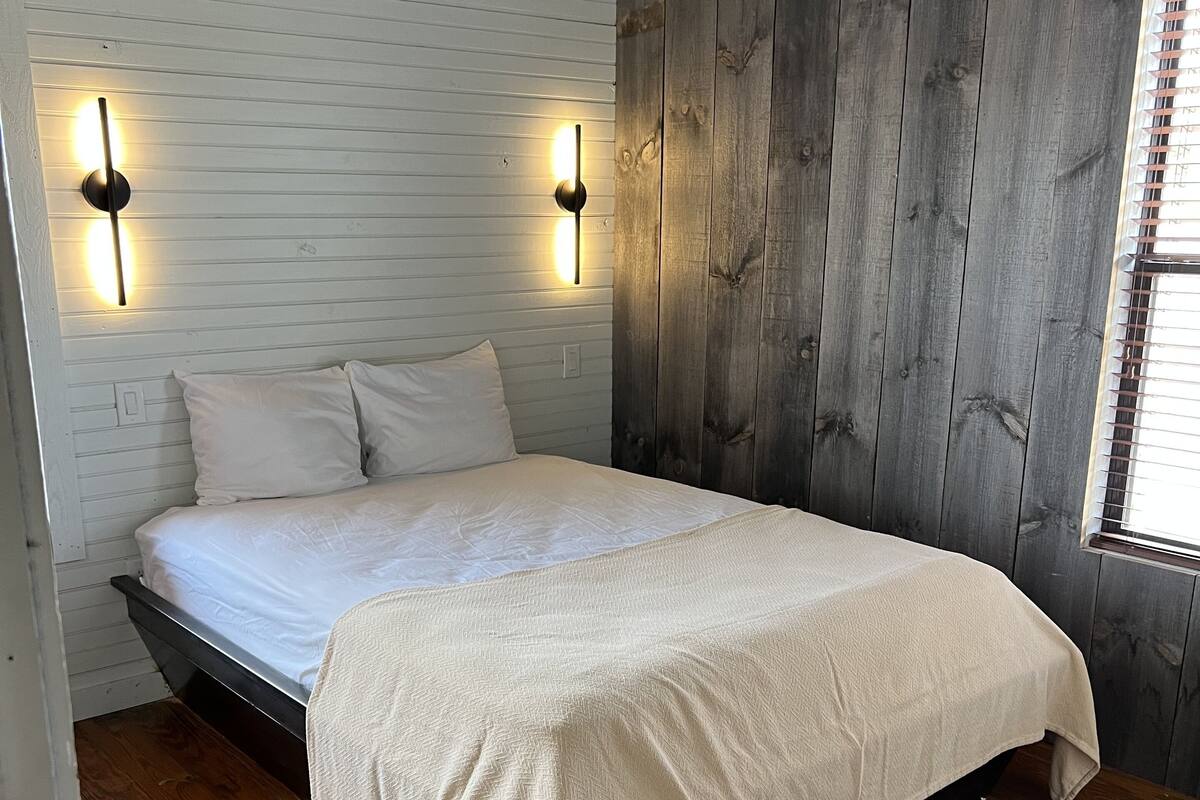 Ein Schlafzimmer mit Bett, Holzwänden und einem Fenster.