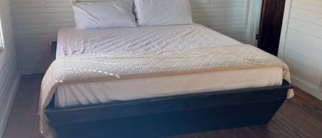 Un dormitorio con una cama, dos luces en la pared y una puerta de madera.