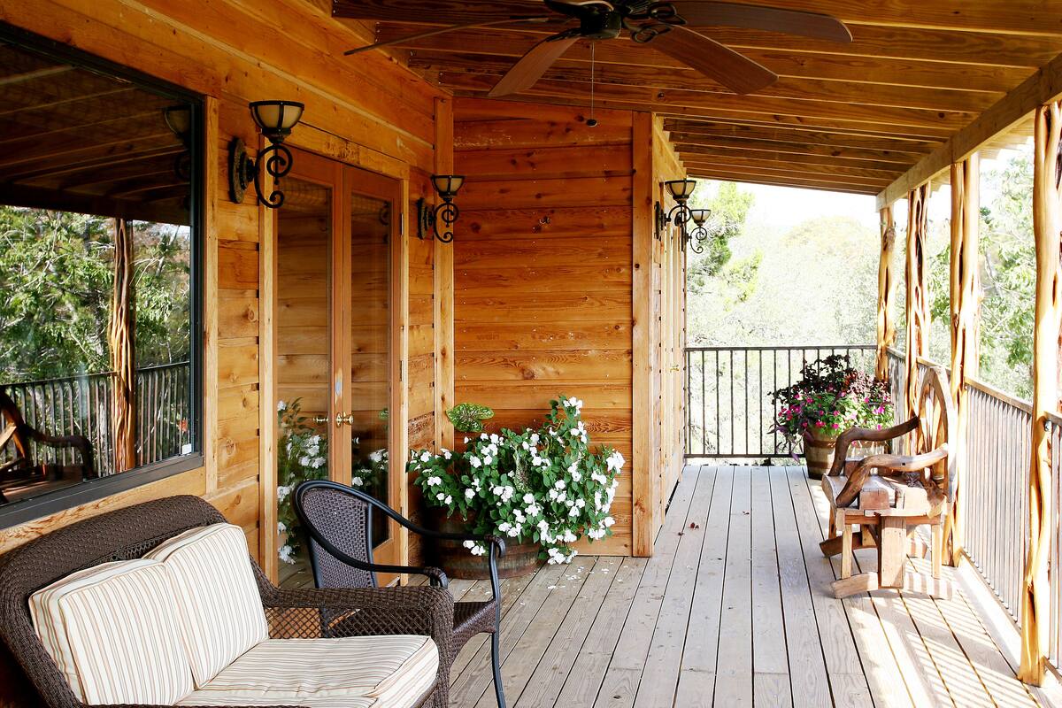 Eine Holzterrasse mit Deckenventilator, Sitzgelegenheiten und Topfpflanzen.