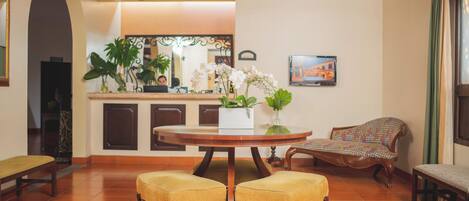 A dining area with a round table, two yellow cushioned chairs, a ceiling fan, and a sofa.