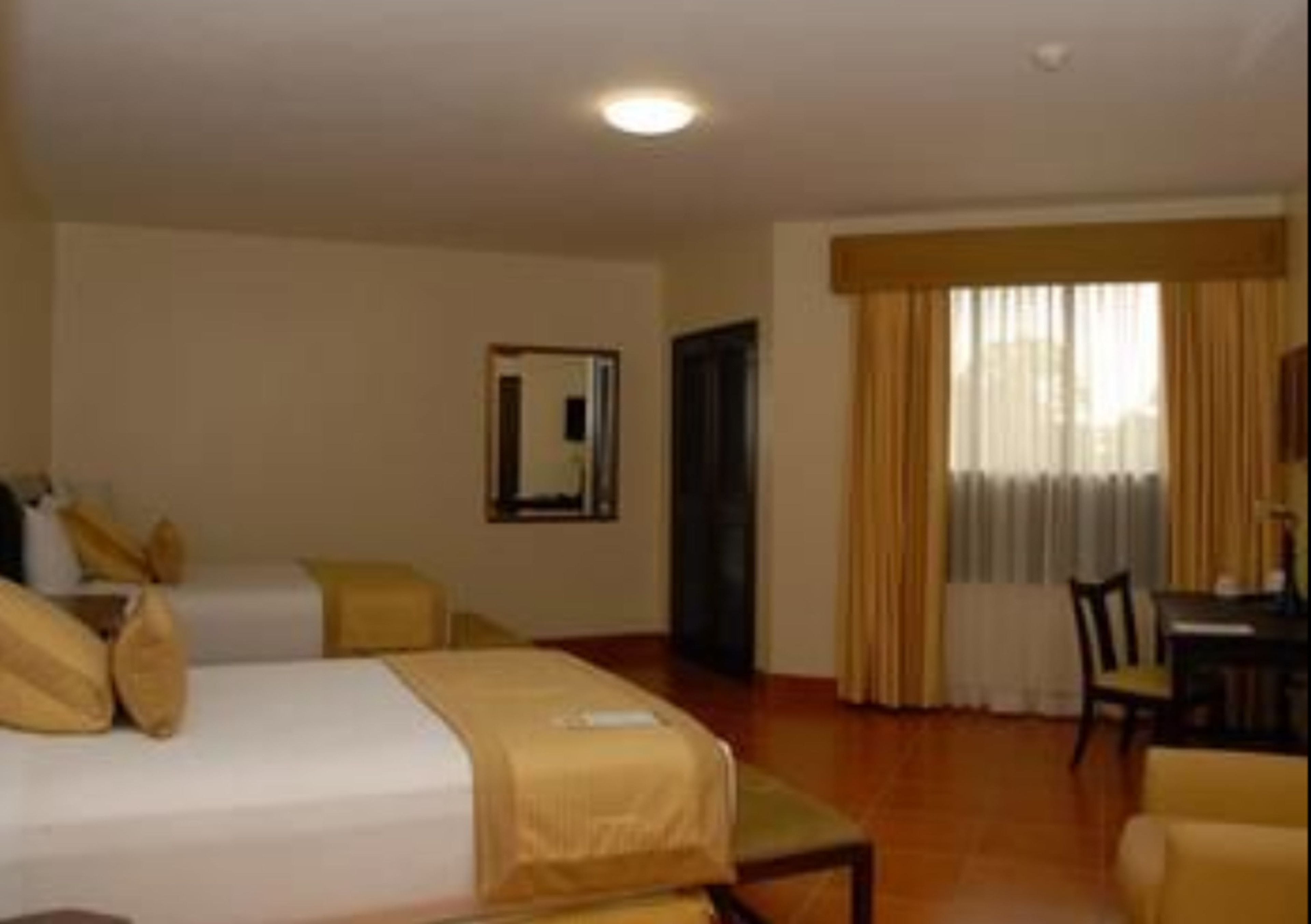 A hotel room with two beds, a dining table, and a chair.