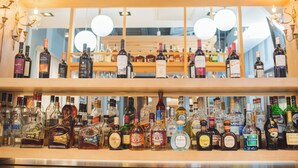 Un bar avec plusieurs étagères remplies de bouteilles de différents types d’alcool.