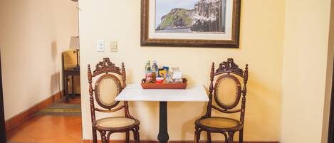 A dining area with a table and two chairs, a framed picture on the wall, and a tray of condiments on the table.