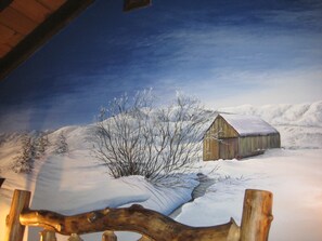 Un mural de un paisaje nevado con una cabaña de madera.