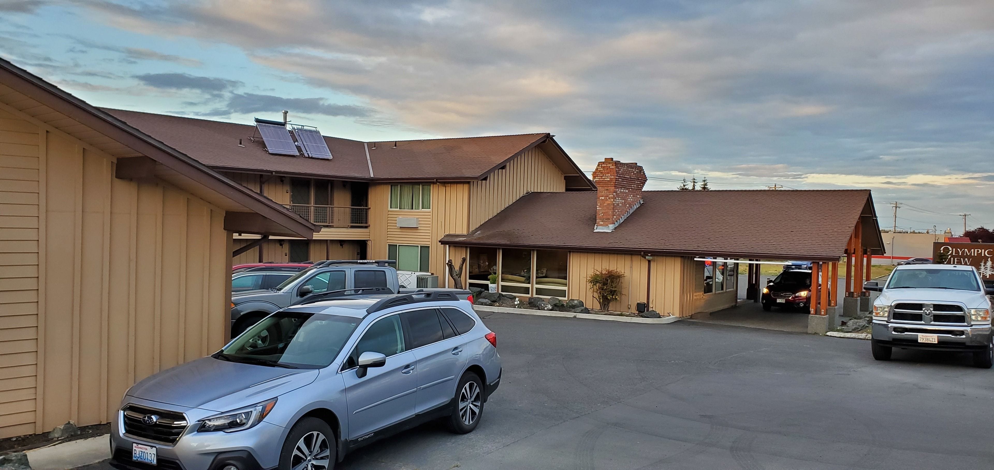 Un edificio con estacionamiento, paneles solares en el techo y un letrero que dice "Olympic View".