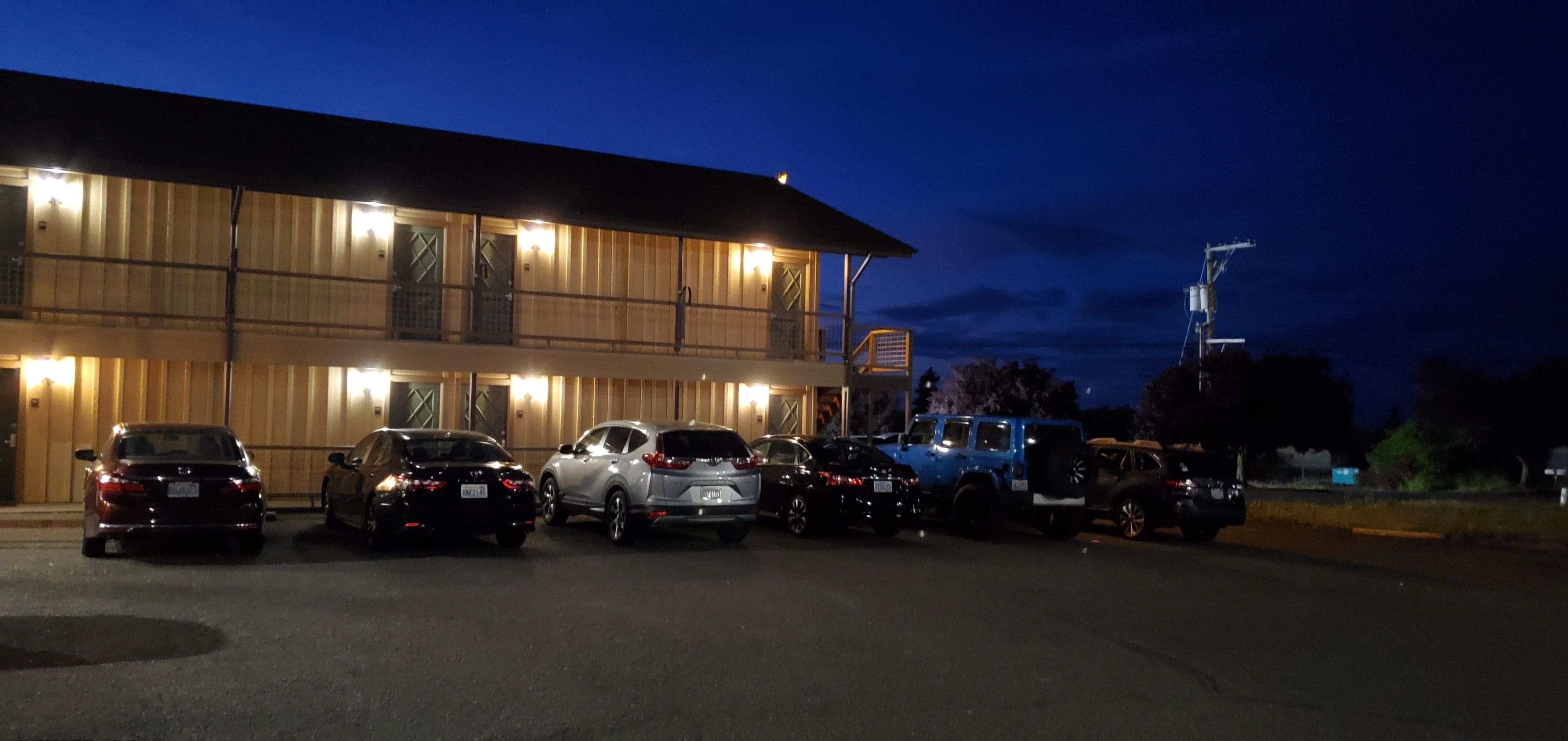 A hotel with a parking lot filled with cars.