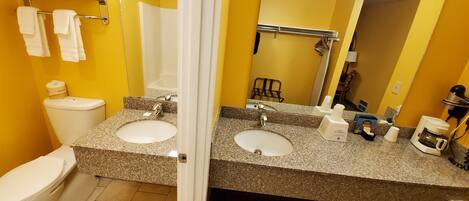 A bathroom with two sinks, a toilet, a shower, and a mirror.