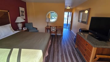 A hotel room with a bed, a desk, a chair, a television, and a window.