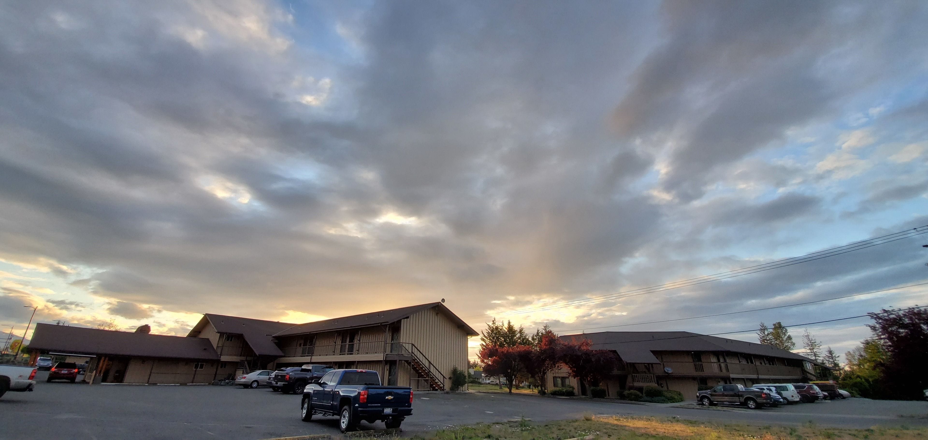 A motel with multiple parking spaces, a covered parking area, and a large building with a flat roof.