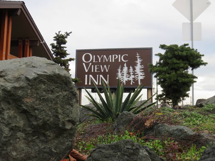 Naamplaatje voor het Olympic View Inn, met een berg en silhouet van een dennenboom.