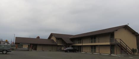 A two-story building with a flat roof and a single-story annex. There is a car parked in front.