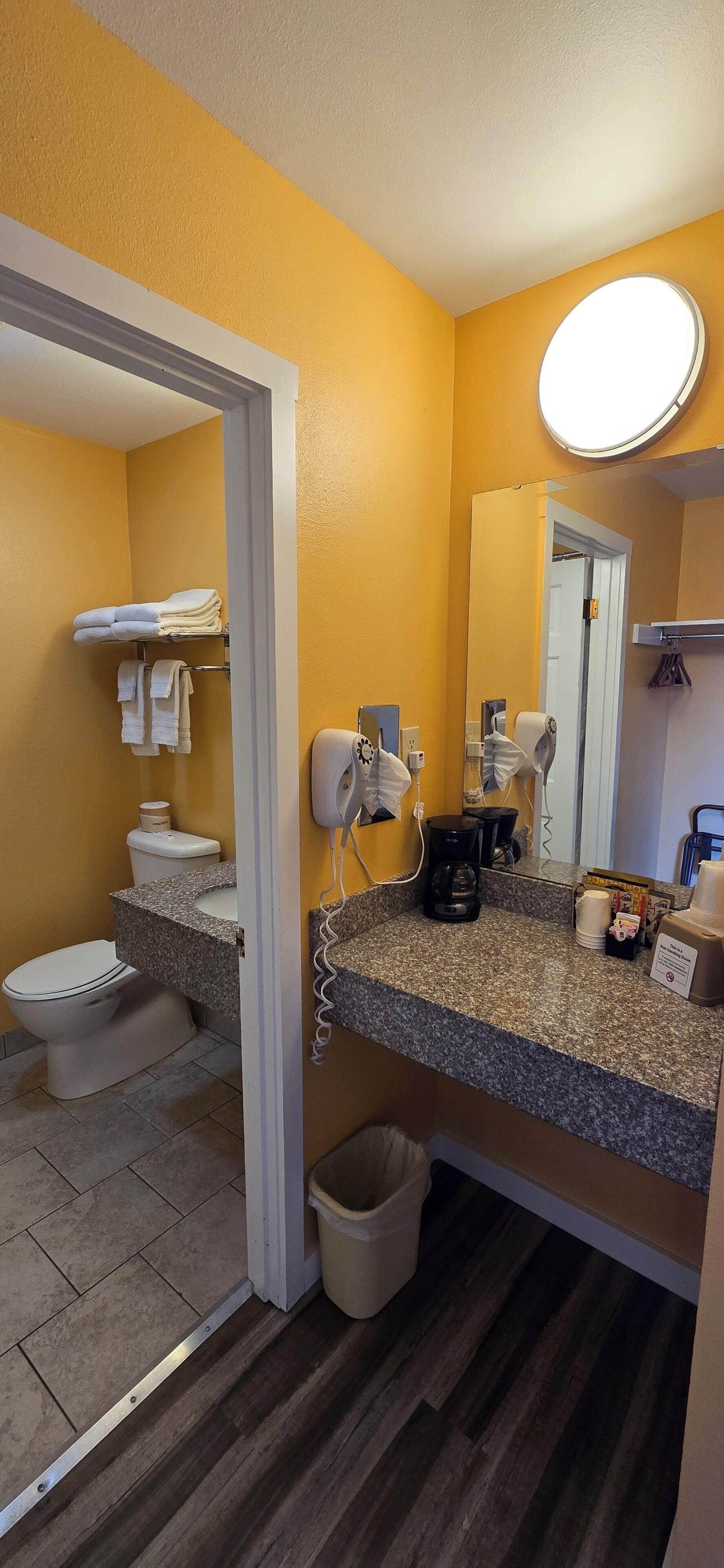 A bathroom with a toilet, sink, and mirror.