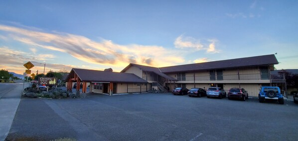 A two-story building with a parking lot, a sign for Olympic View Inn, and several cars parked in front.