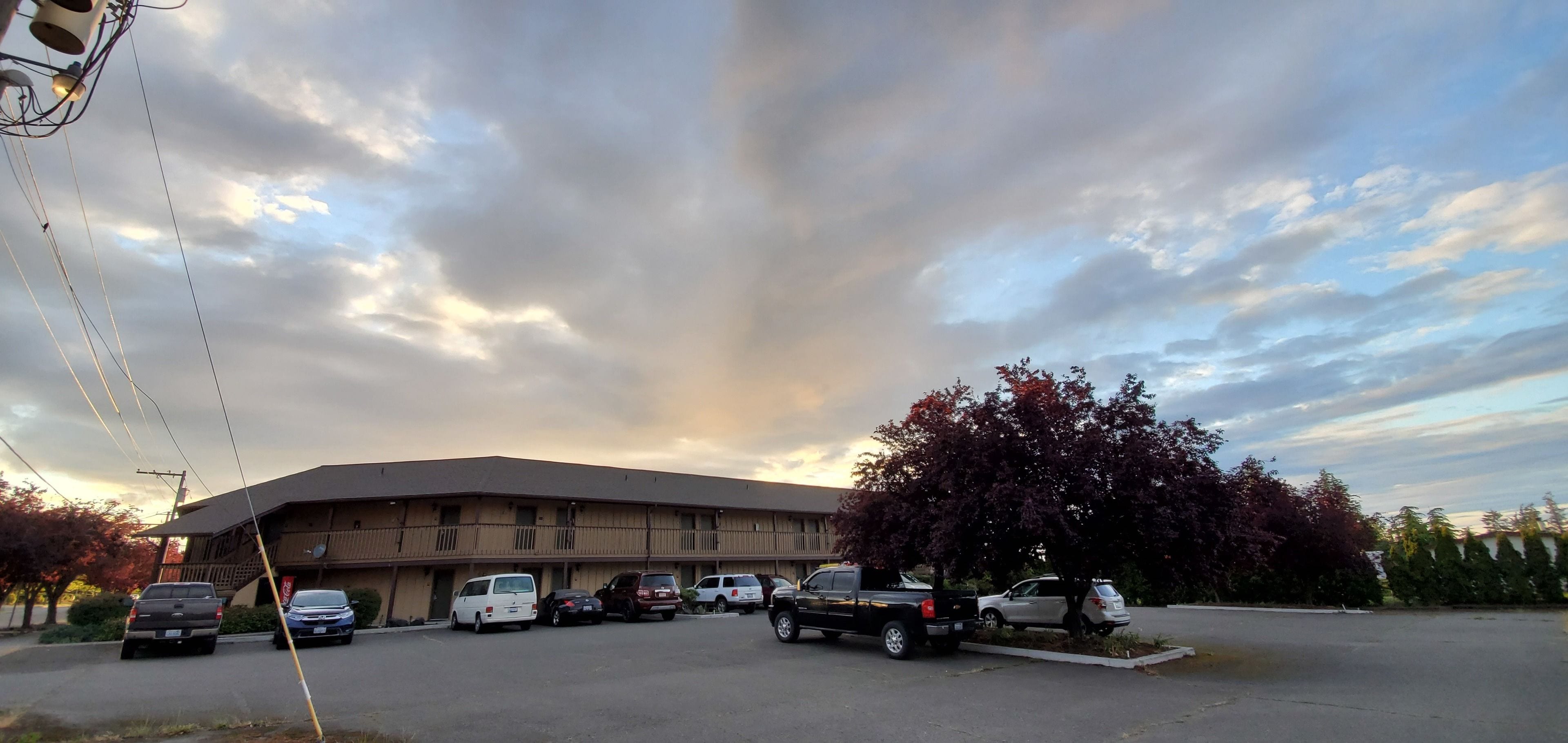 A parking lot with several cars and a building with a flat roof and multiple windows.
