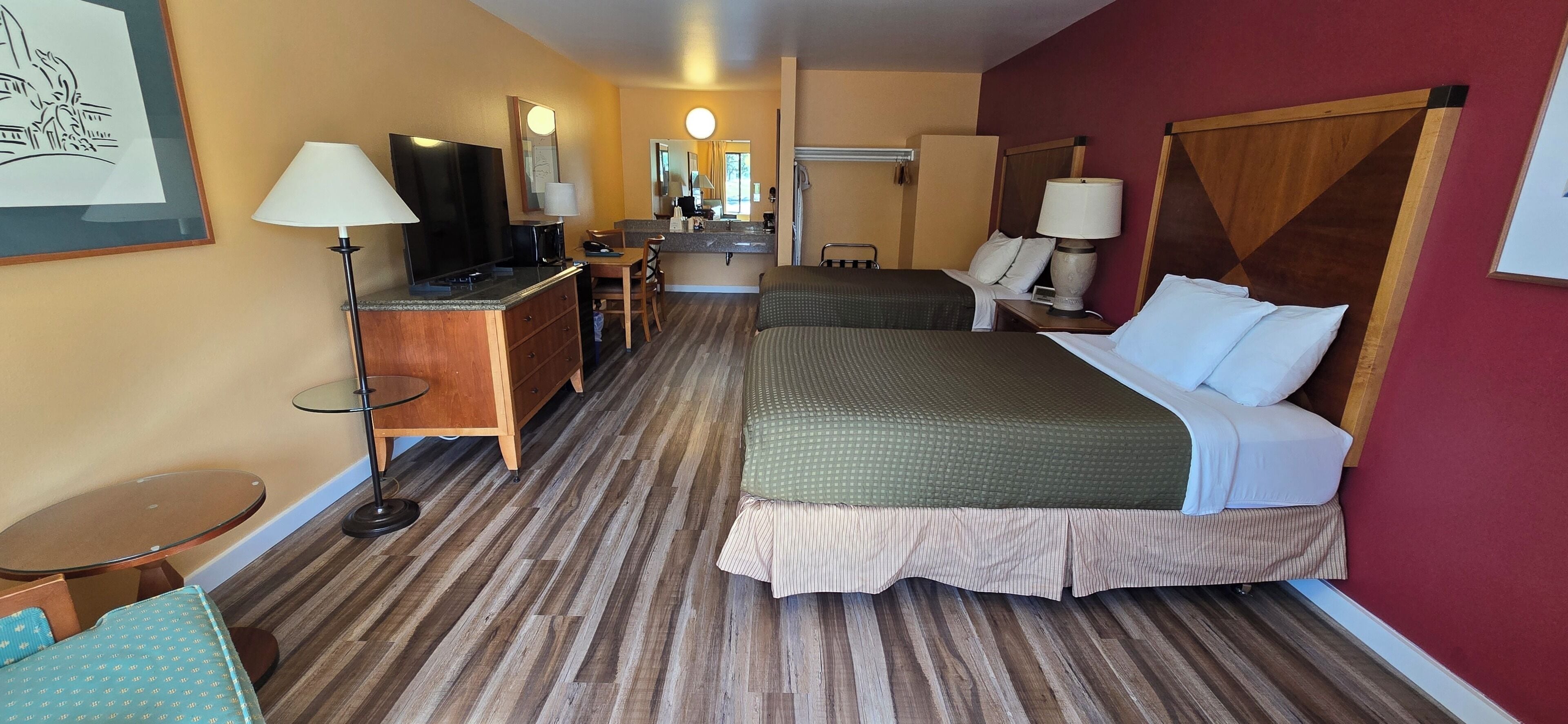 A hotel room with a bed, a desk with a chair, a television, and a mirror.