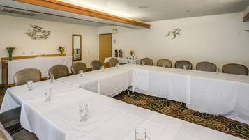 A conference room with long tables, chairs, and white tablecloths.