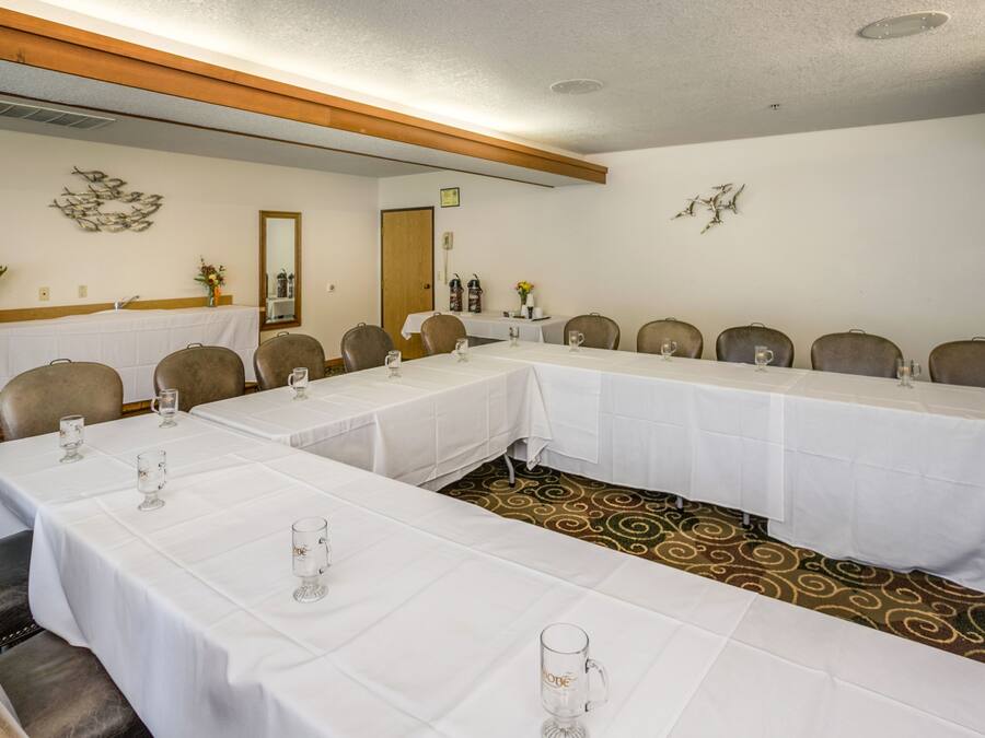 A conference room with long tables, chairs, and white tablecloths.