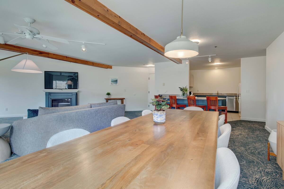 A spacious dining area with a long wooden table, comfortable seating, and a ceiling fan.