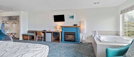 Habitación de hotel con cama, escritorio, chimenea, bañera y vistas al exterior.