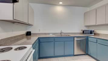 Una cocina con estufa blanca, armarios azules, microondas y lavavajillas.