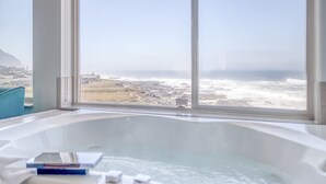 A bathroom with a large bathtub, a view of the ocean, and a window. - Adobe Resort (Yachats)