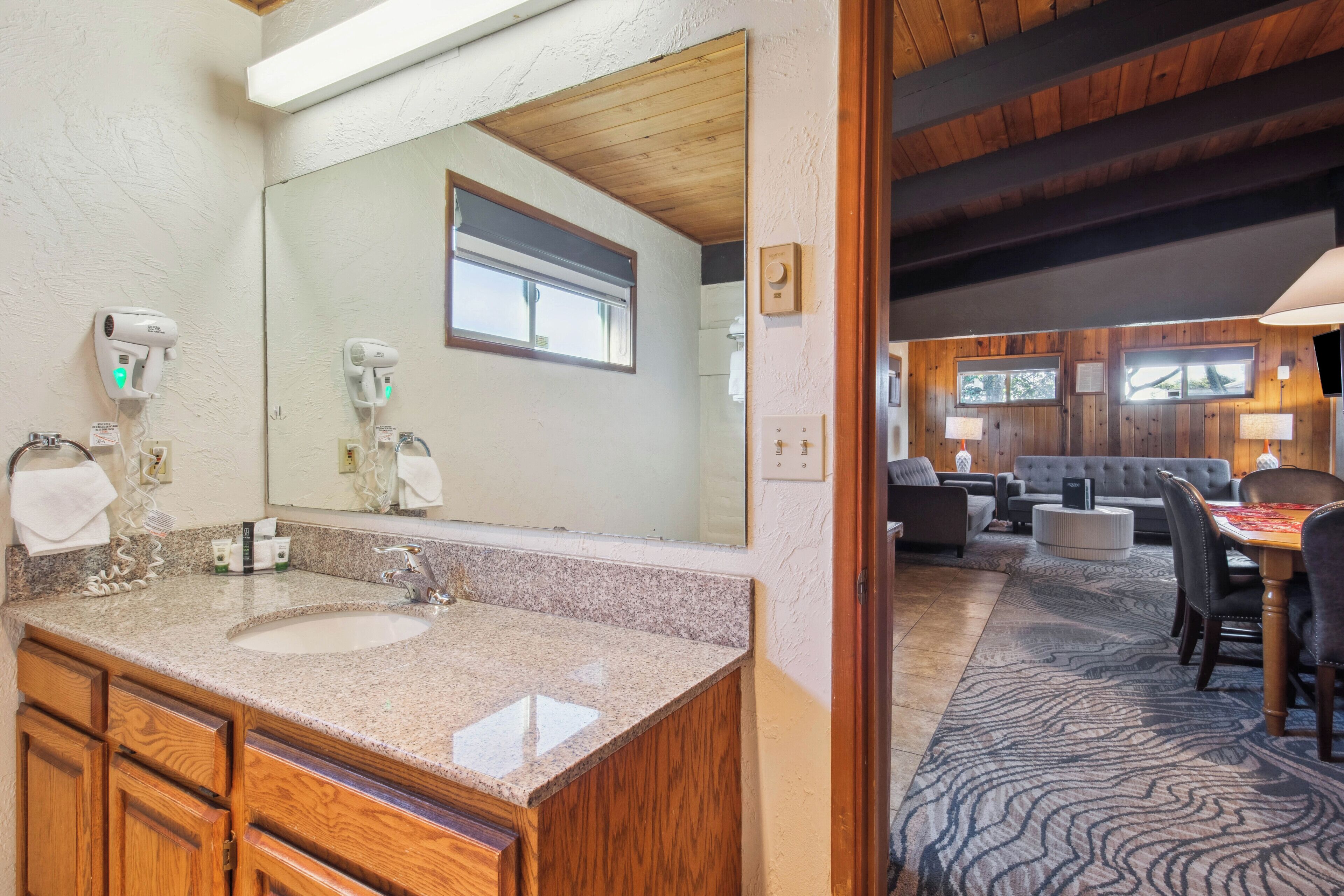 A bathroom with a double sink, wooden cabinets, and a large mirror.