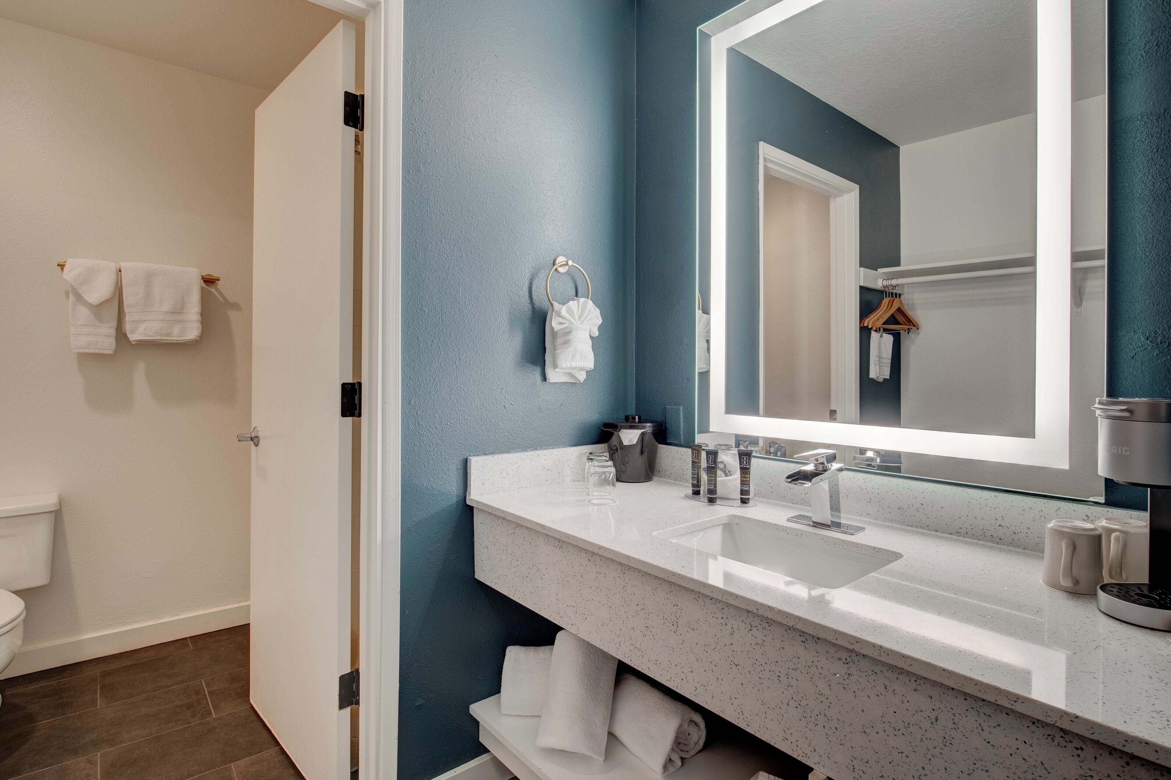 A modern bathroom with a white sink, a large mirror, and a toilet.