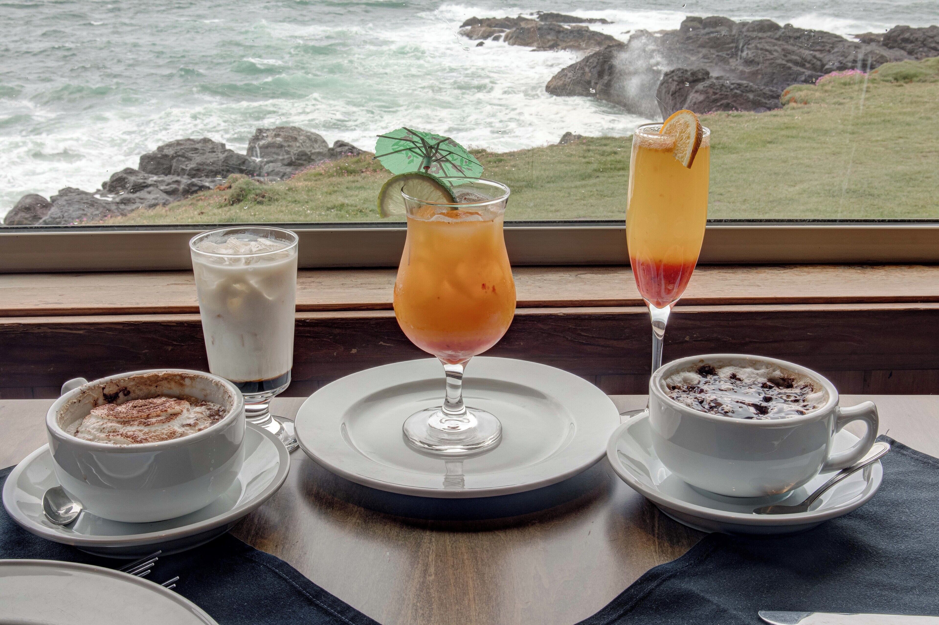 Three beverages on a table with a view of the ocean.