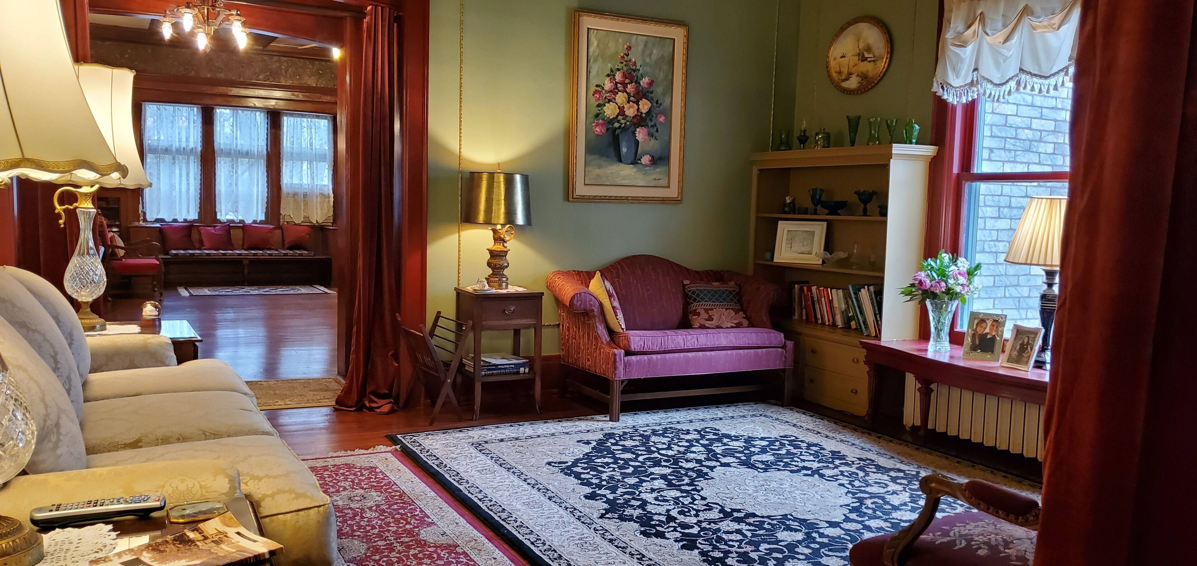 Una sala de estar acogedora con un sofá, una mesa de centro, una alfombra, una estantería y un cuadro en la pared.