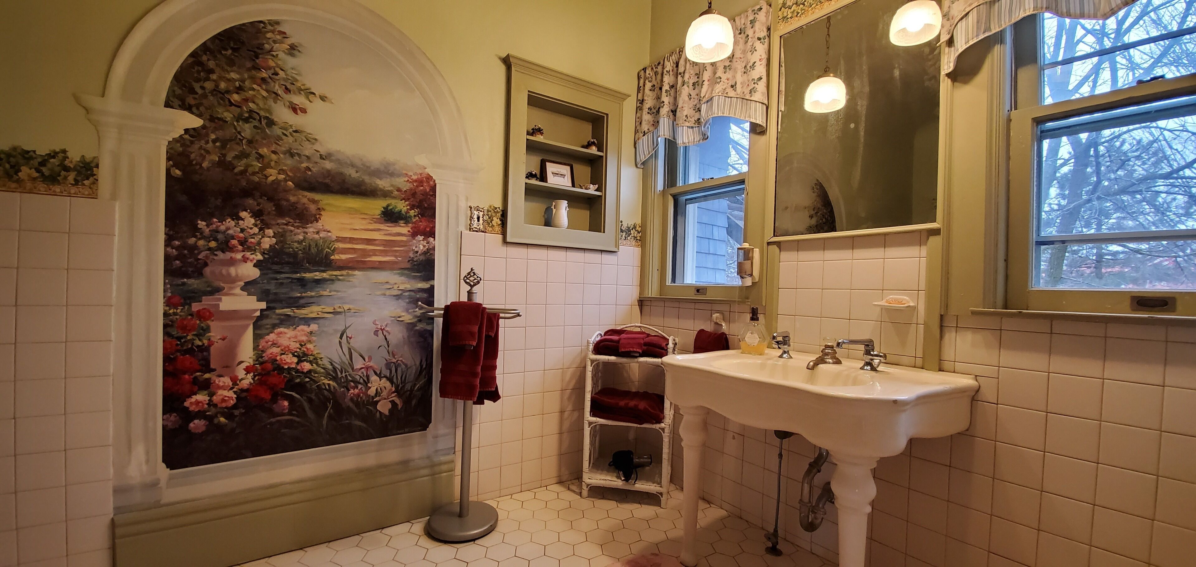 Un baño con un mural, un lavabo y una ventana.