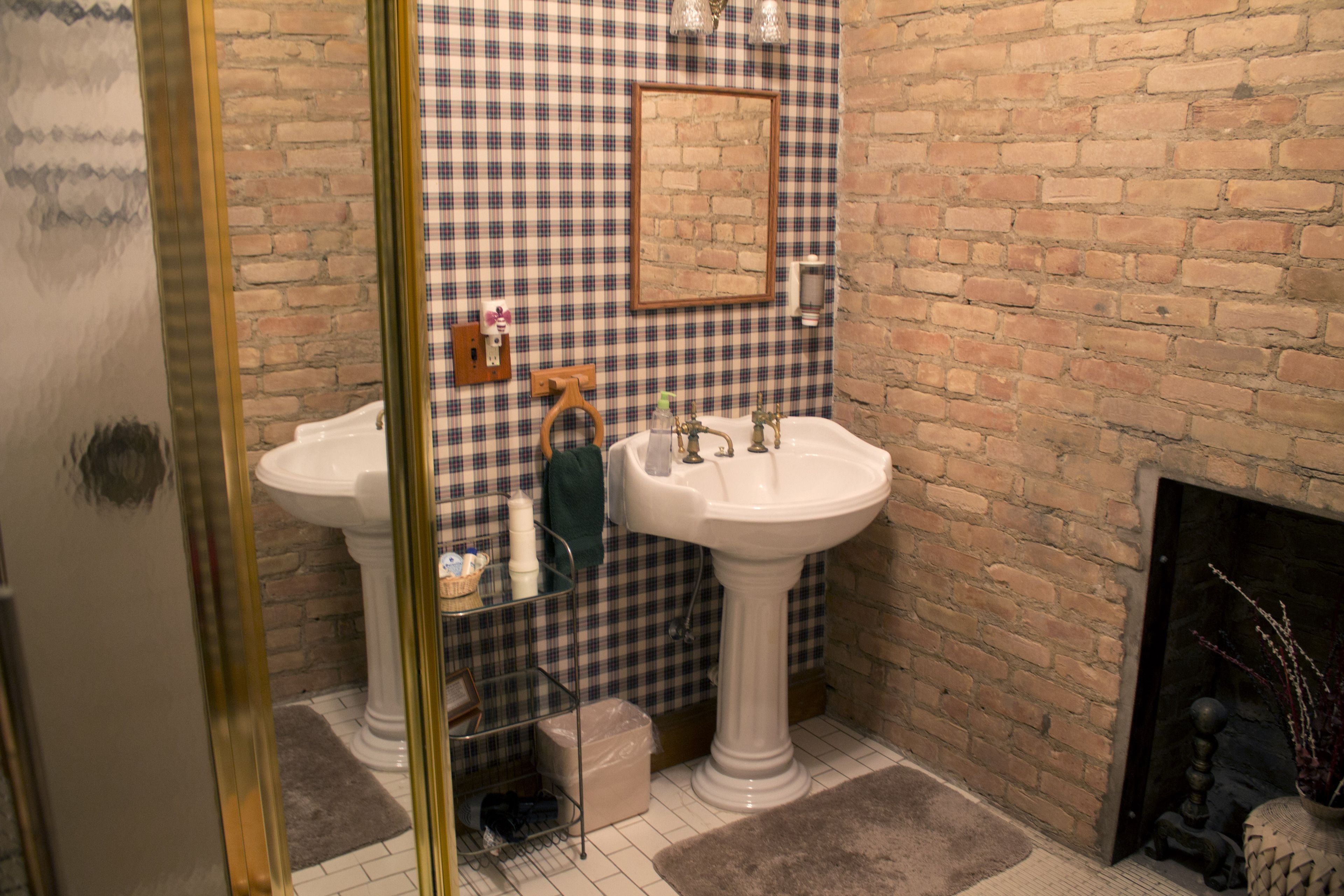 A bathroom with two sinks, a mirror, a brick wall, and a fireplace.